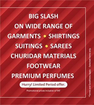 Promotional text banner detailing K.M. Trading's "BIG SLASH" discounts on garments, shirtings, suitings, sarees, churidar materials, footwear, and premium perfumes, displayed over a red patterned background.